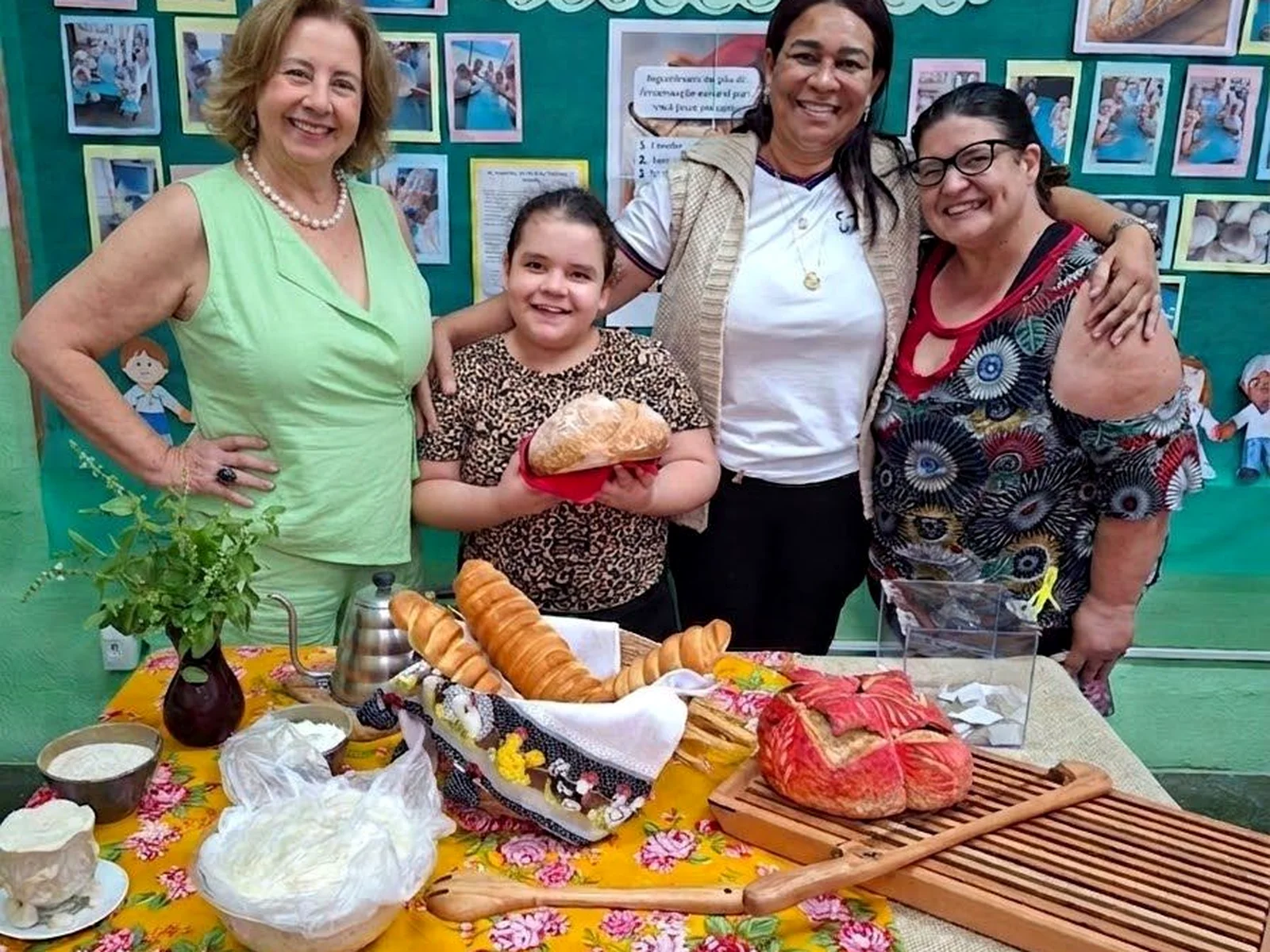 Grupo reunido em atividade escolar, ao lado de uma mesa com alimentos.